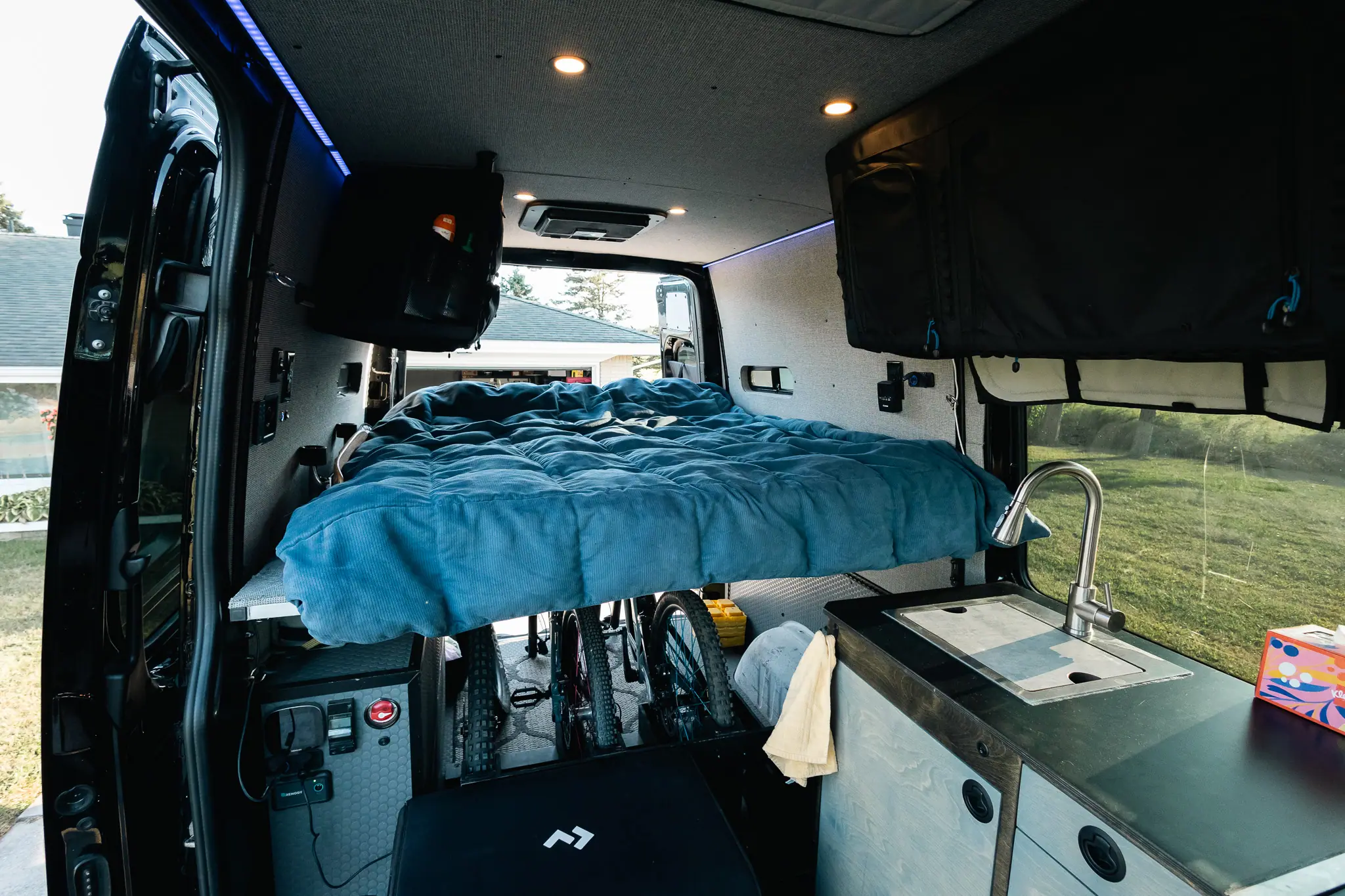 Raised rear bed in a Sprinter camper van with mountain bikes stored in the garage underneath