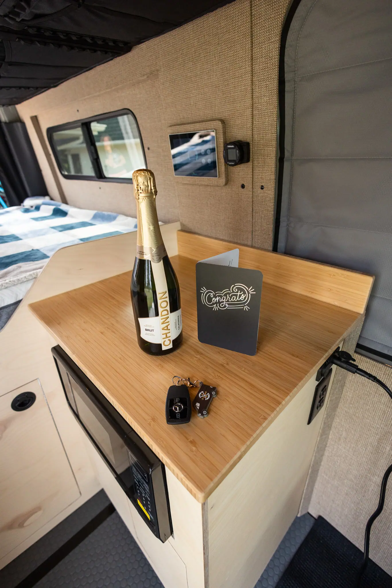 Keys and a congratulations card on the bamboo countertop of a finished Sprinter camper van